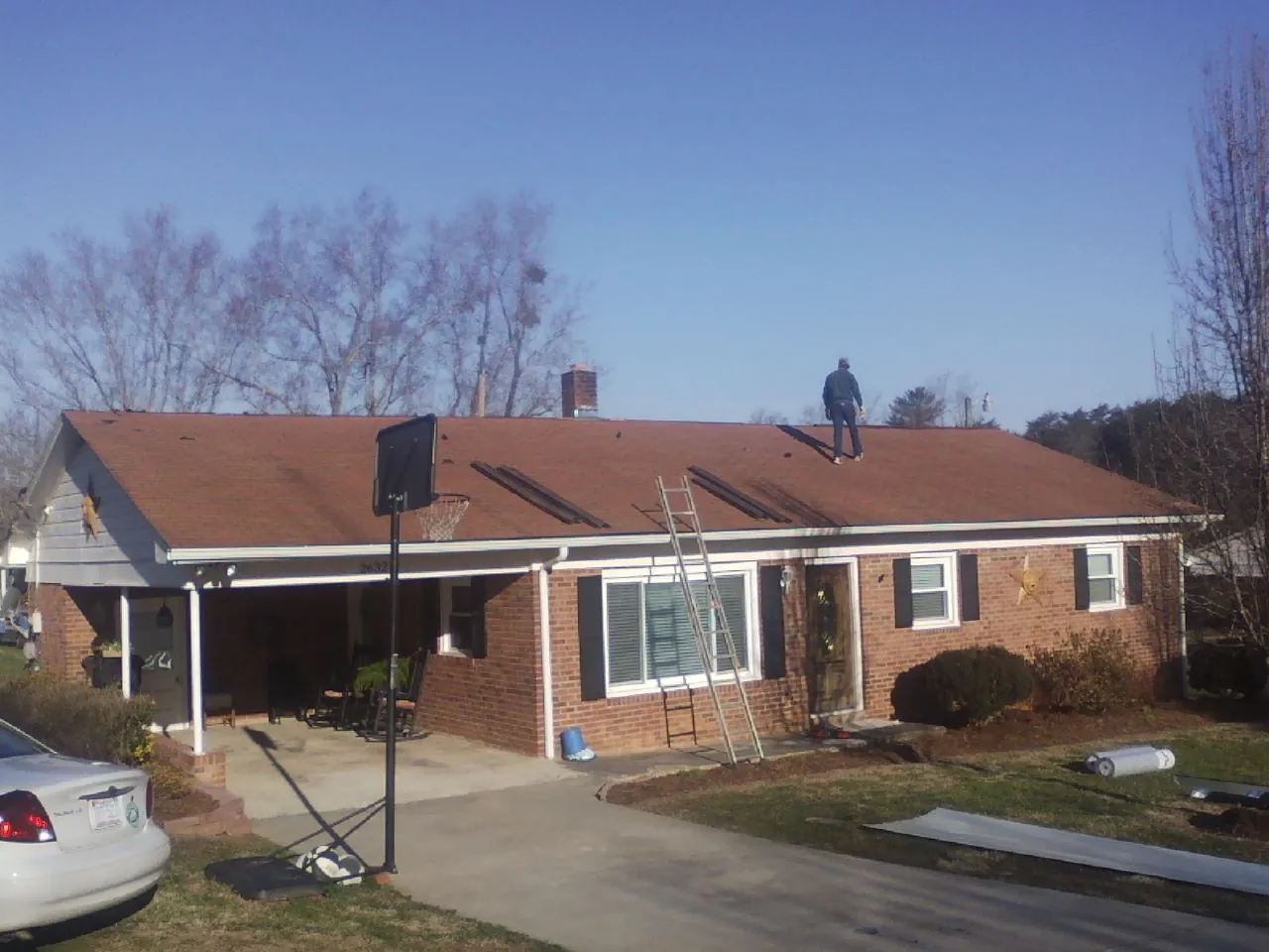 Roofer stripping a shingle roof on a brick ranch before metal panels in Placerville