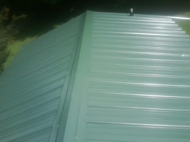 New green metal panels meeting at the ridge of a roof — Flat Roof Repair work by our crew in Placerville