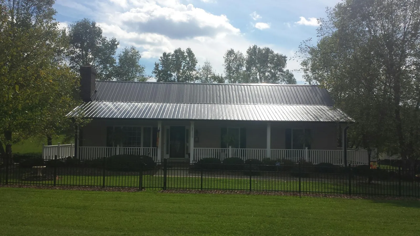 Gray metal roof on a brick ranch with a full width front porch — Gutter Guard Installation work by our crew in Placerville